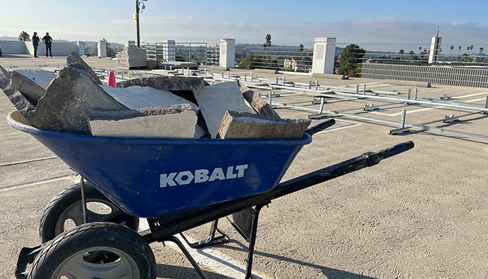 Wheelbarrow filled with broken concrete at a construction site.