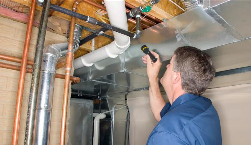 Worker inspecting plumbing and ventilation system.
